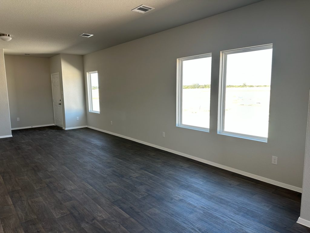 Image of home living room with wood-look floor, white walls, and windows