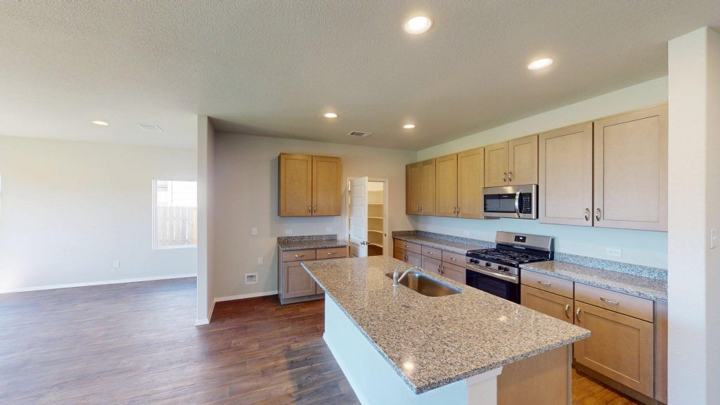 Image of a kitchen with granite countertops with light brown cabinets and black kitchen appliances