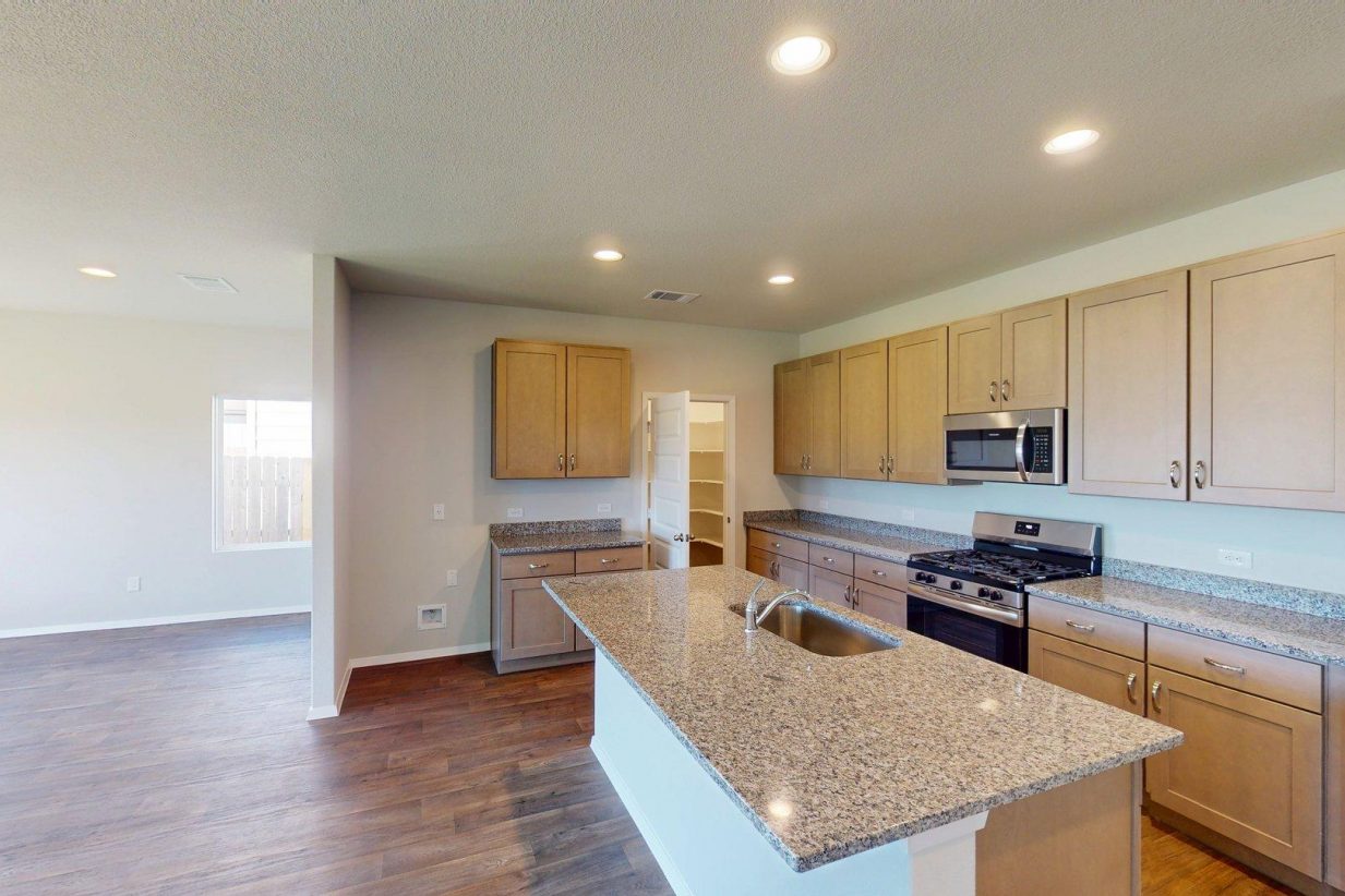 Image of a kitchen with granite countertops with light brown cabinets and black kitchen appliances
