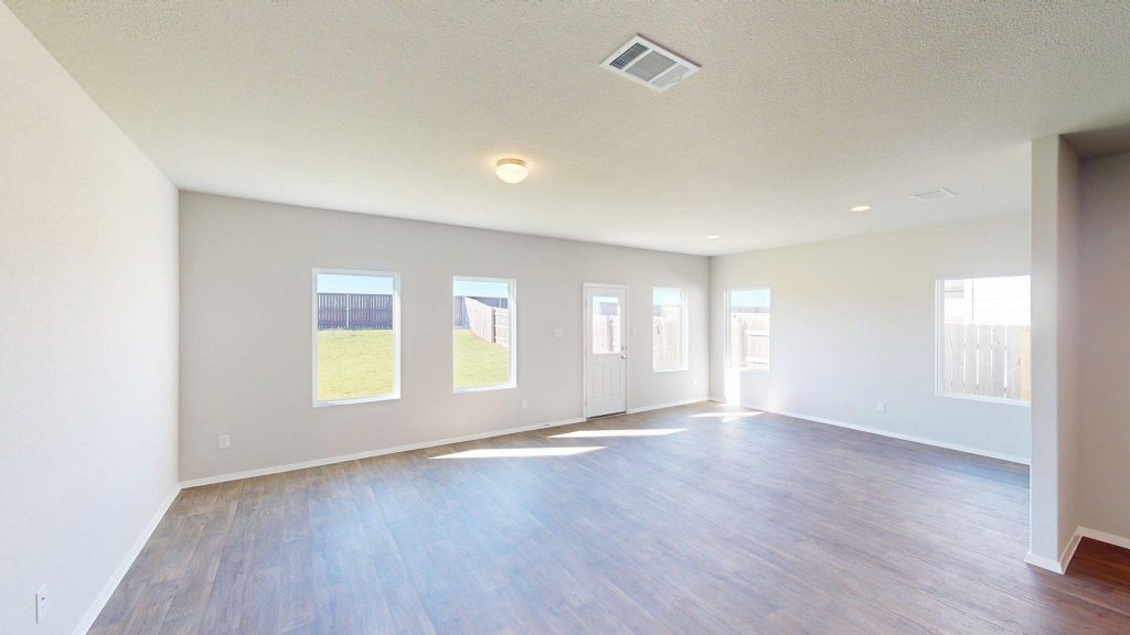 Image of a one story home living room with brown wood-like flooring and light grey painted walls with windows and natural lighting