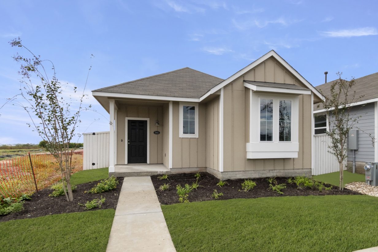 Image of exterior of one story home with greenery and a blue sky