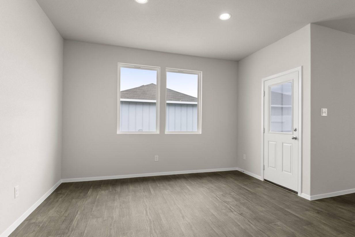 Image of dining room with brown flooring and light grey walls with two windows and a white door