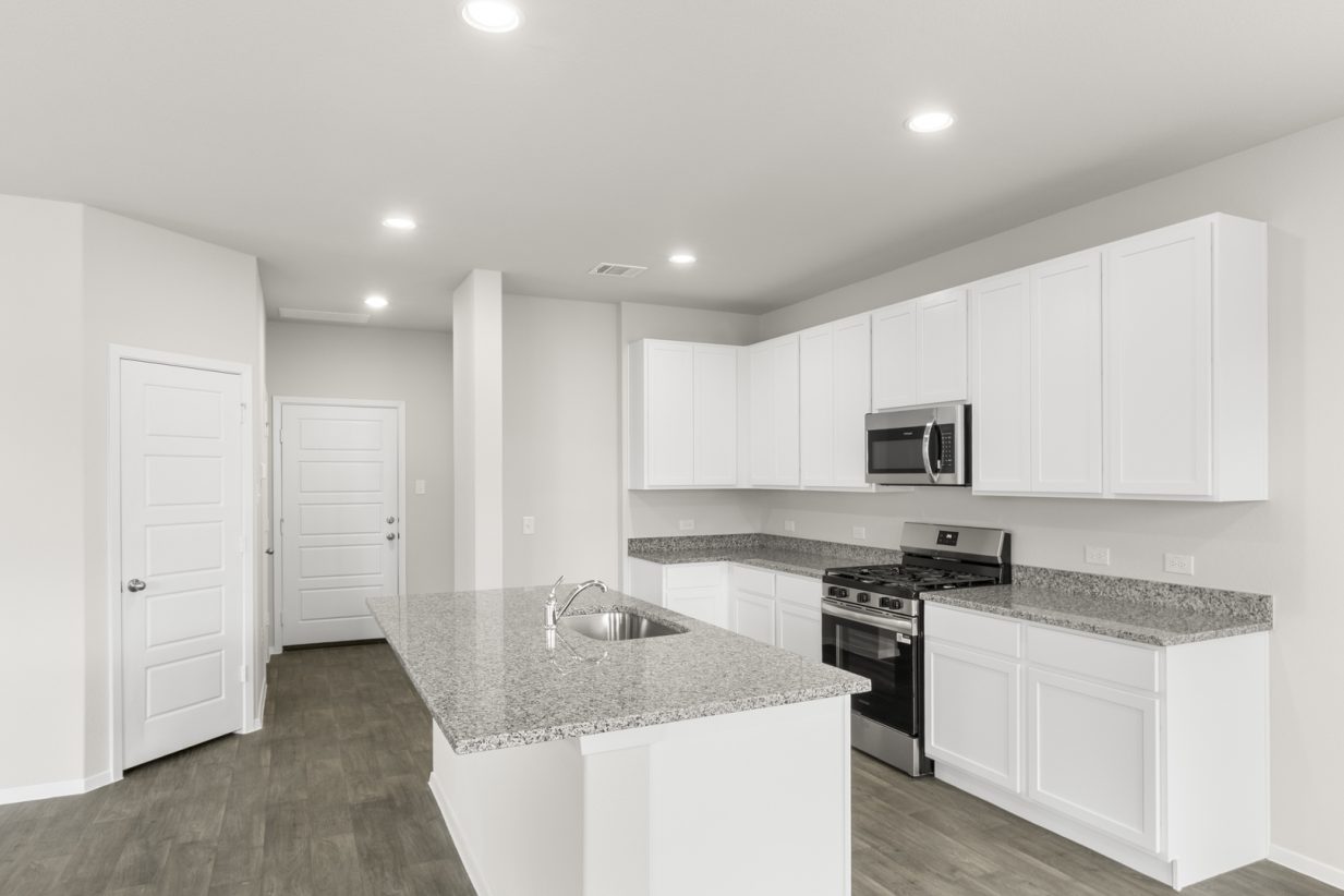 Image of a kitchen with white cabinets and black appliances with grey counters