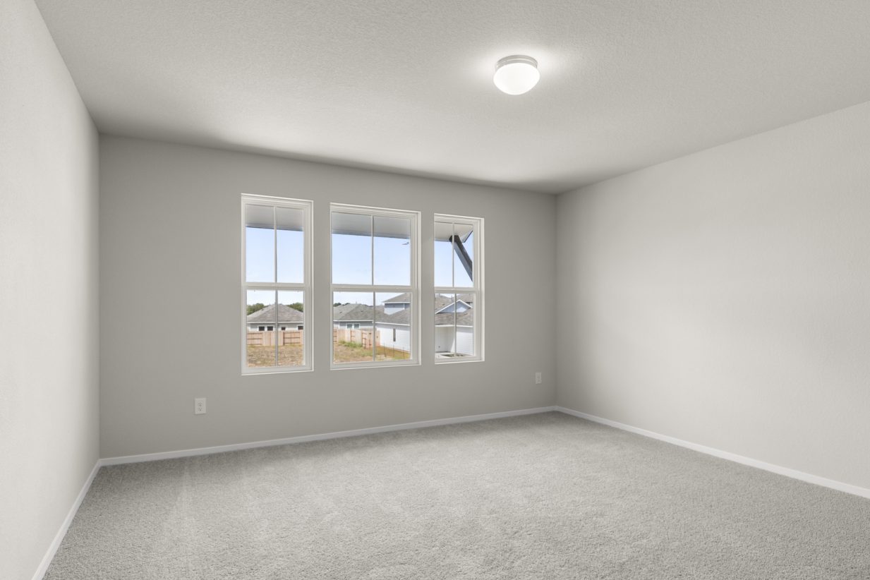 Image of primary bedroom with light grey carpet and walls with three windows
