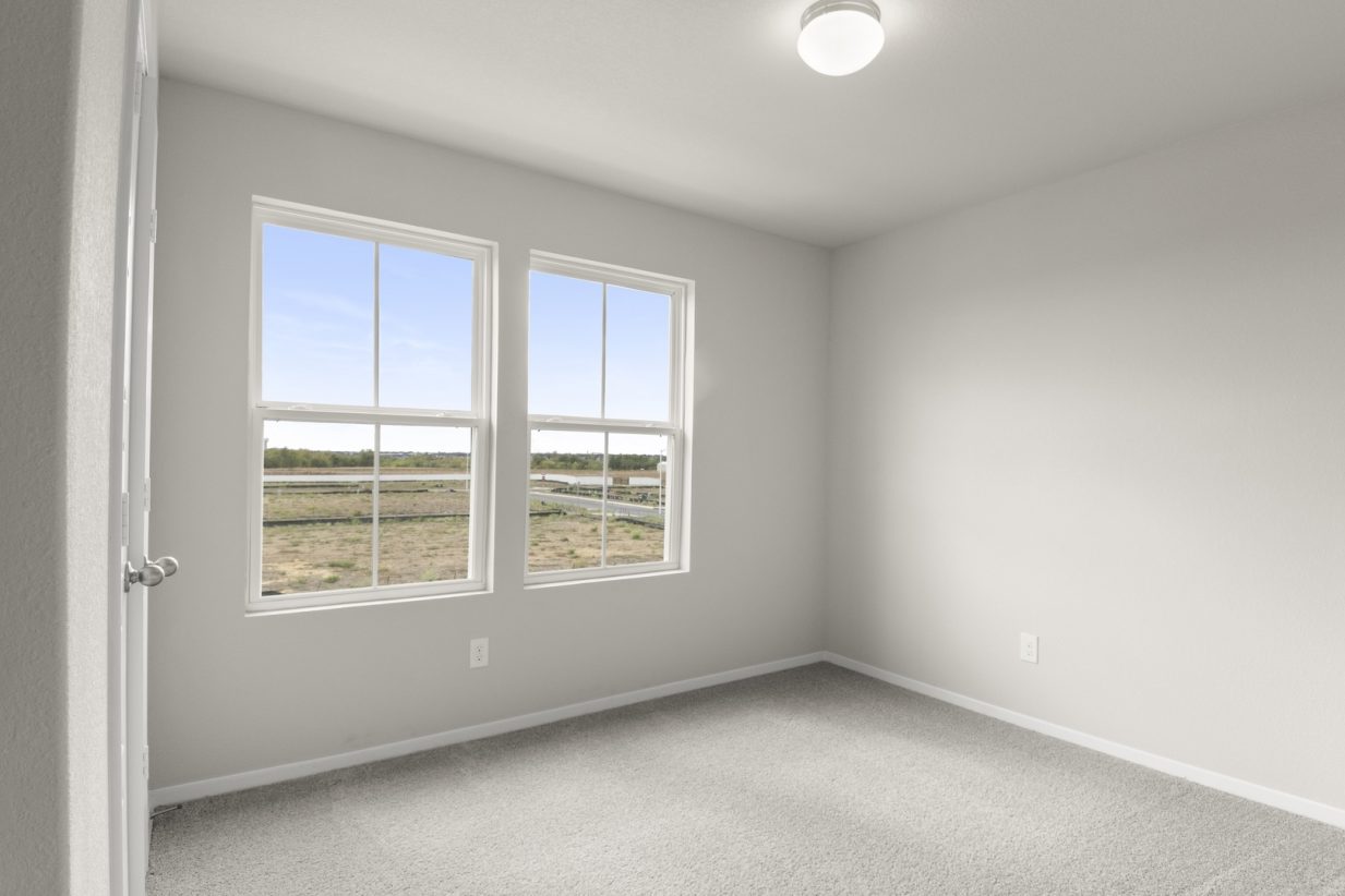 Image of bedroom with light grey walls and carpet with two windows
