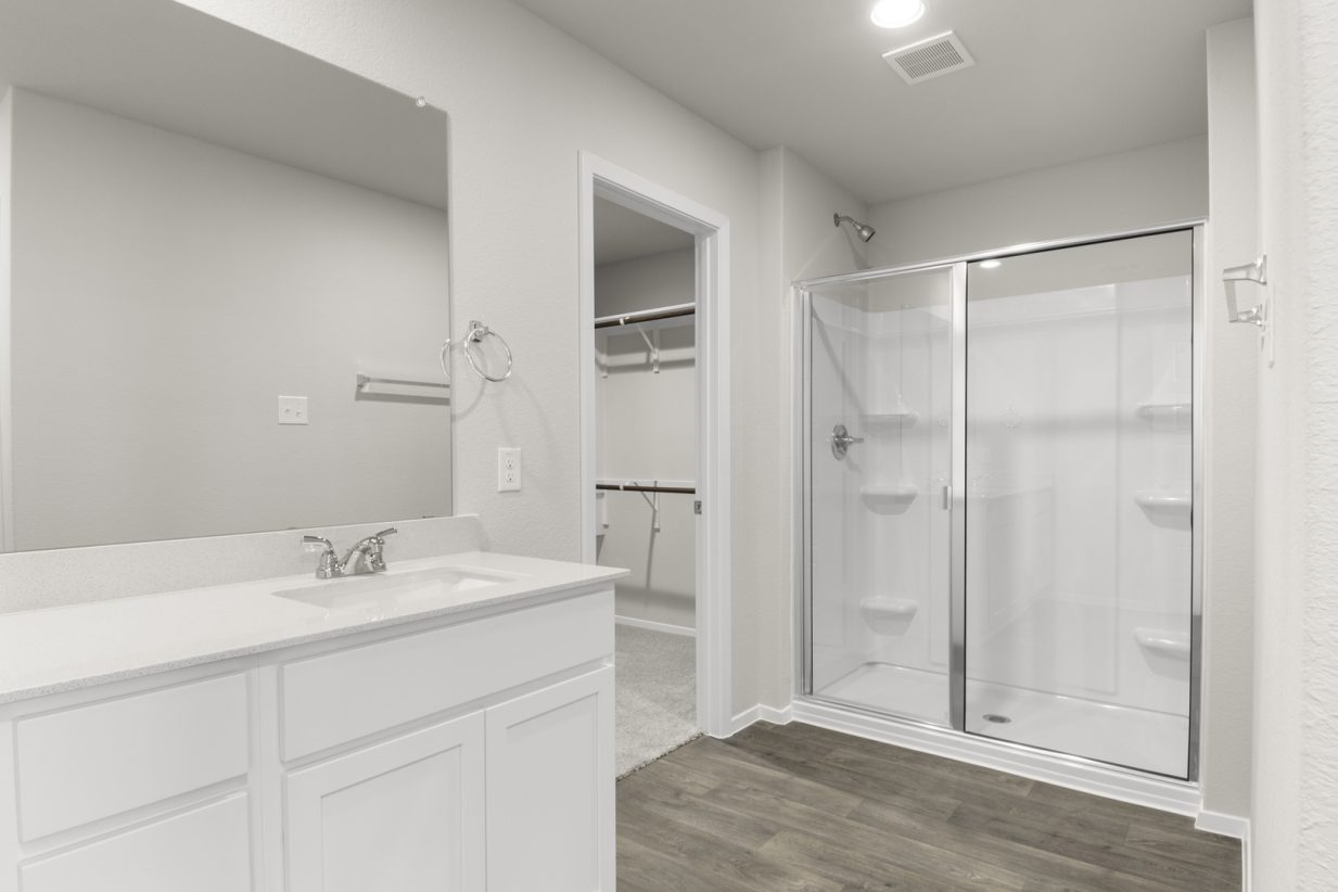Image of primary bathroom with white cabinets and a standing shower