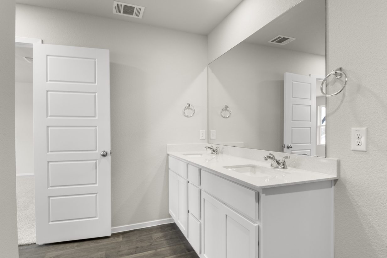 Image of primary bathroom with white cabinets with a mirror and vanity