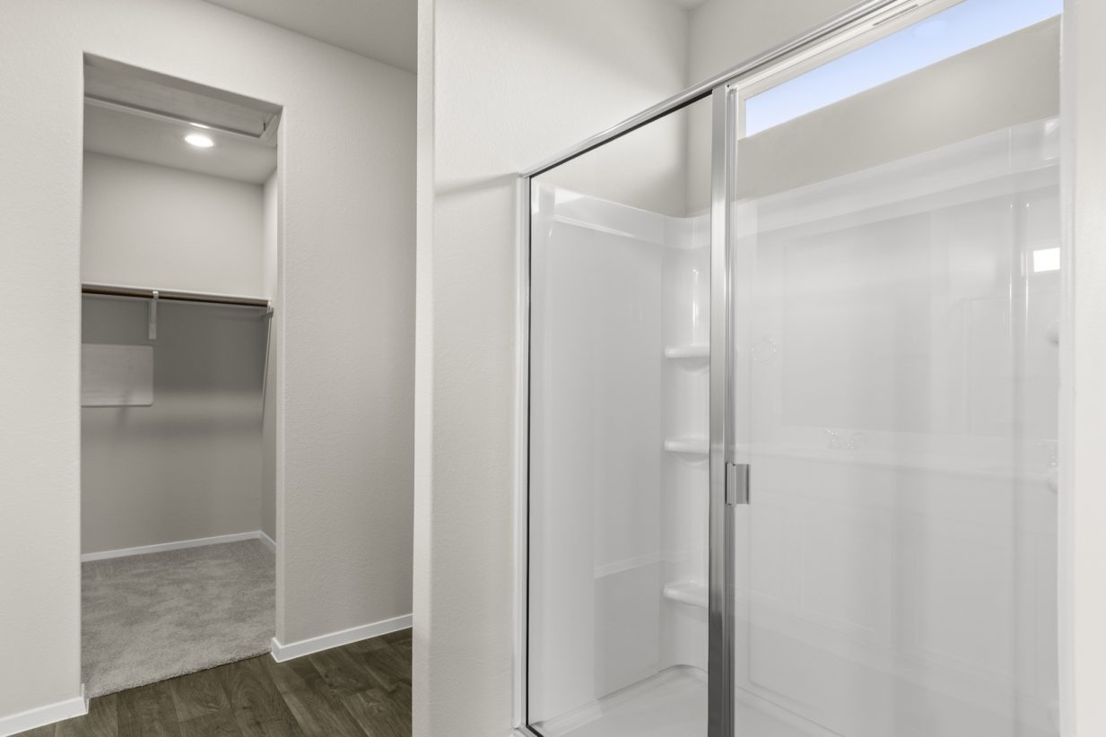Image of primary bathroom with a walk in closet and walk in shower
