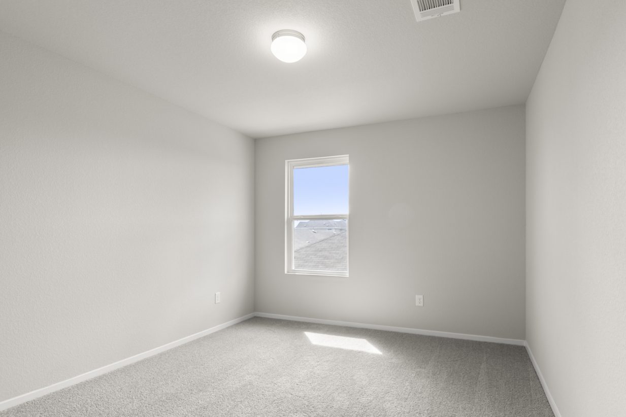 Image of bedroom with light grey carpet and walls with a window
