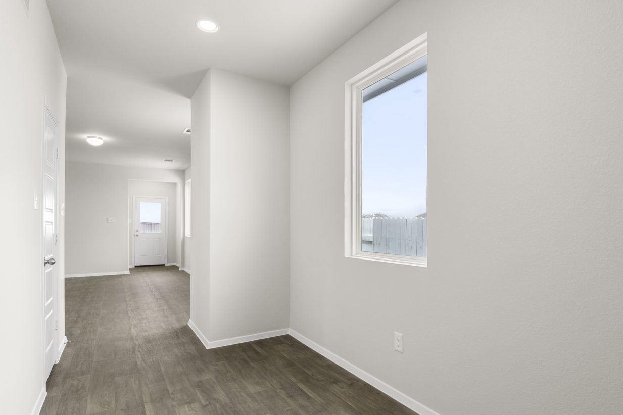Image of a one story foyer with brown floors and light grey walls and a window