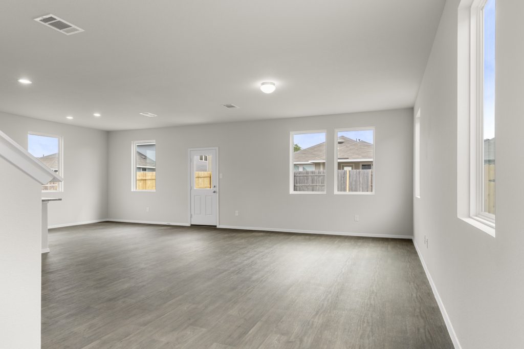 Image of a two story home living room with brown flooring and grey walls with windows