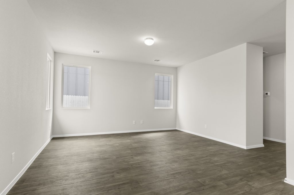 Image of a two story home living room with brown flooring and windows