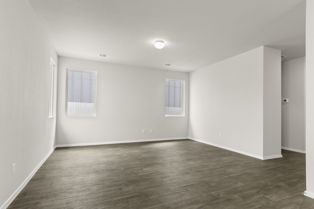 Image of a two story home living room with brown flooring and windows