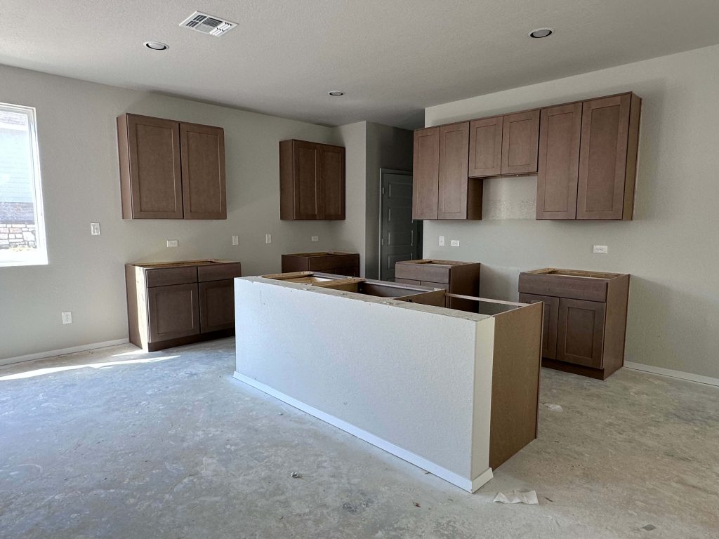 An image of kitchen under construction with brown cabinets and cream painted walls.