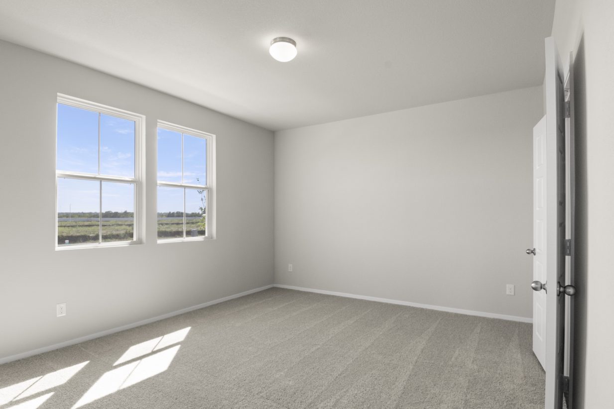 Image of home bedroom with light carpet, white walls, and two windows on one wall