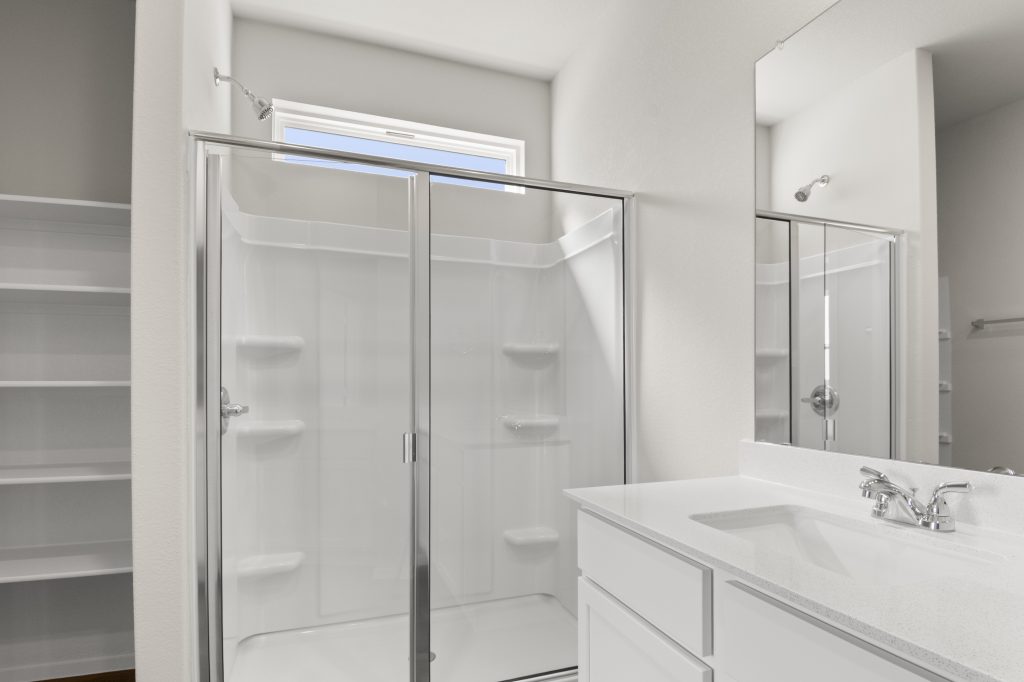 Image of home bathroom with walk-in shower with a window, and white vanity with mirror