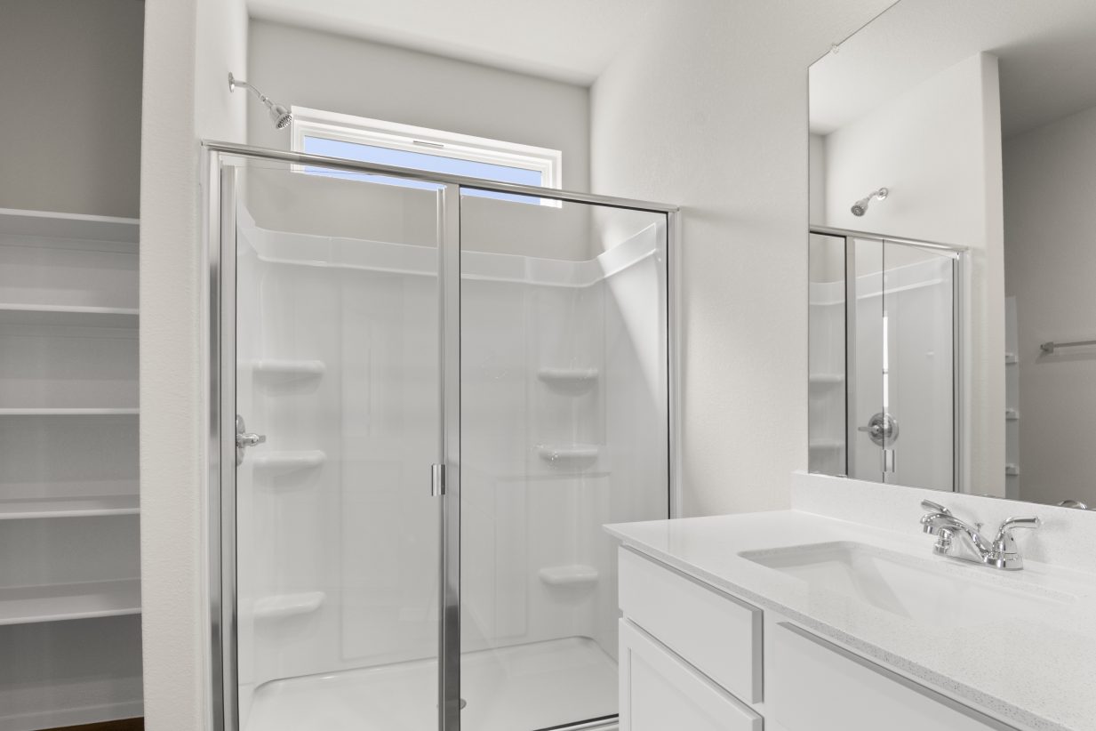 Image of home bathroom with walk-in shower with a window, and white vanity with mirror
