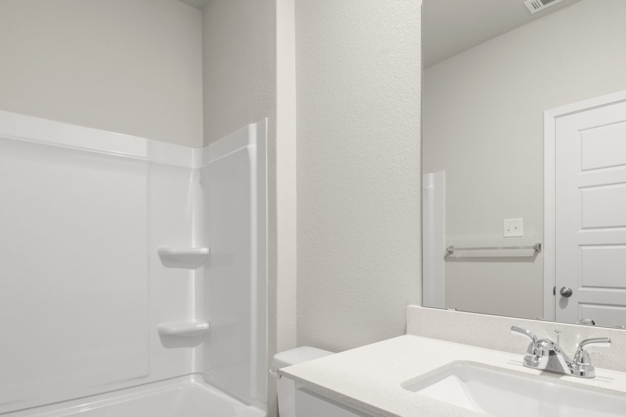 Image of home secondary bathroom with white vanity, mirror, and white tub