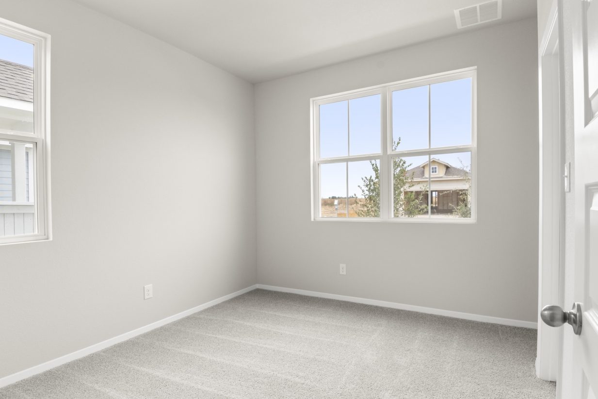 Image of home bedroom with light carpet, white walls, and windows