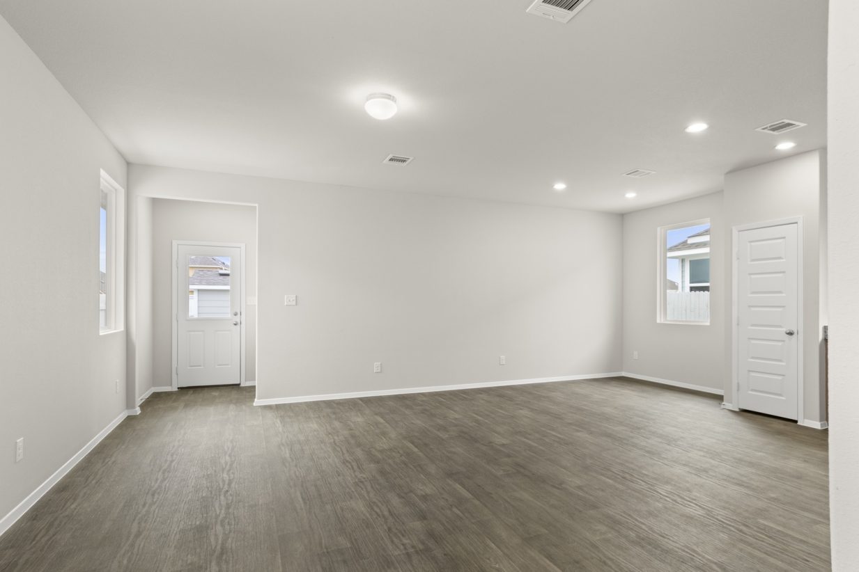 Image of home living room with wood-look flooring, white walls, and windows