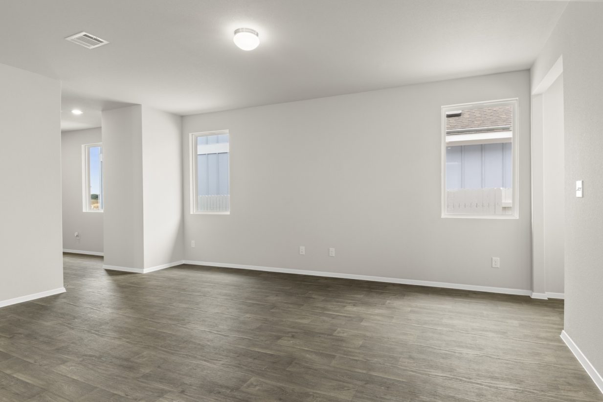 Image of home living room with wood-look flooring, white walls, and windows