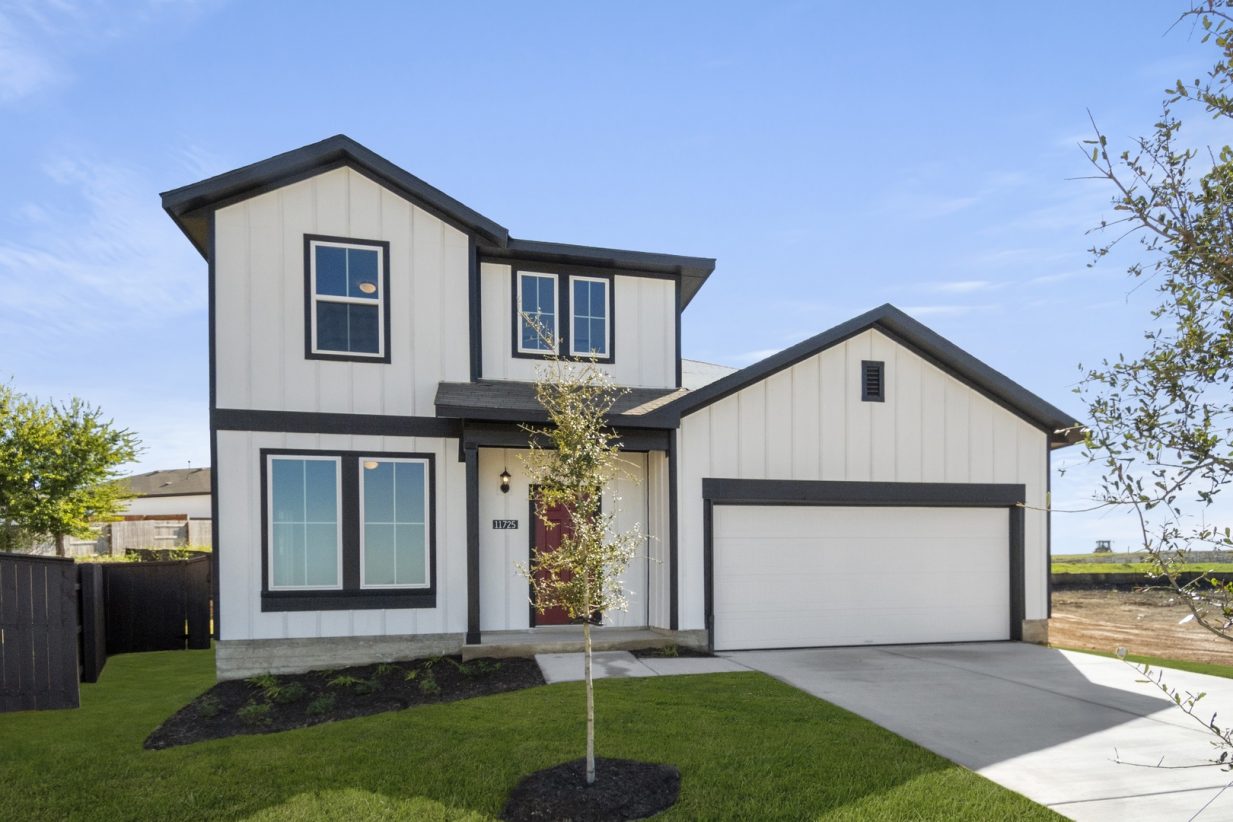 Image of the front exterior of a white farmhouse style two story home with black trim and a red front door with a two car garage and cement driveway