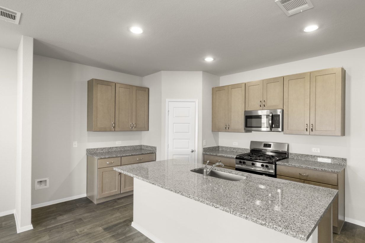 Image of a kitchen with granite countertops with light brown cabinets, black appliances and a center island