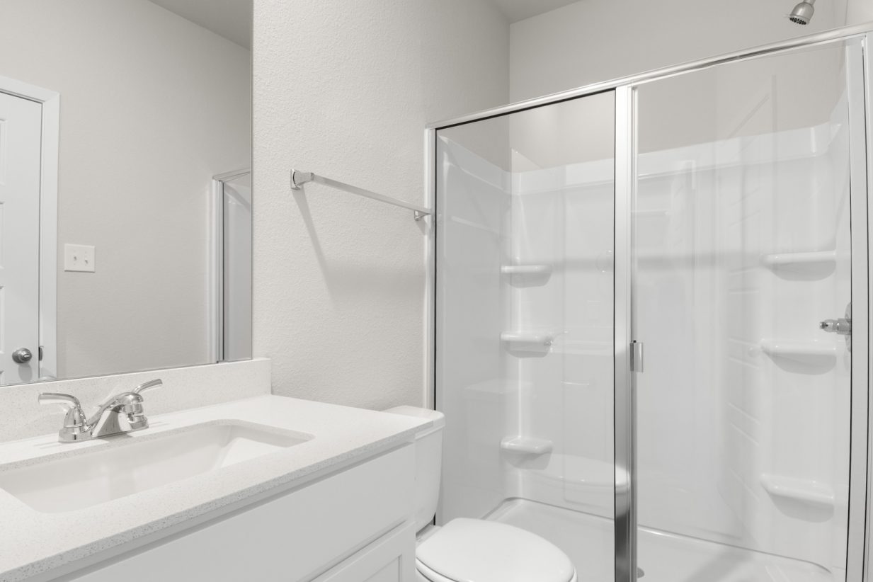 Image of a primary bathroom with white cabinets and a mirror with a vanity and a walk in shower