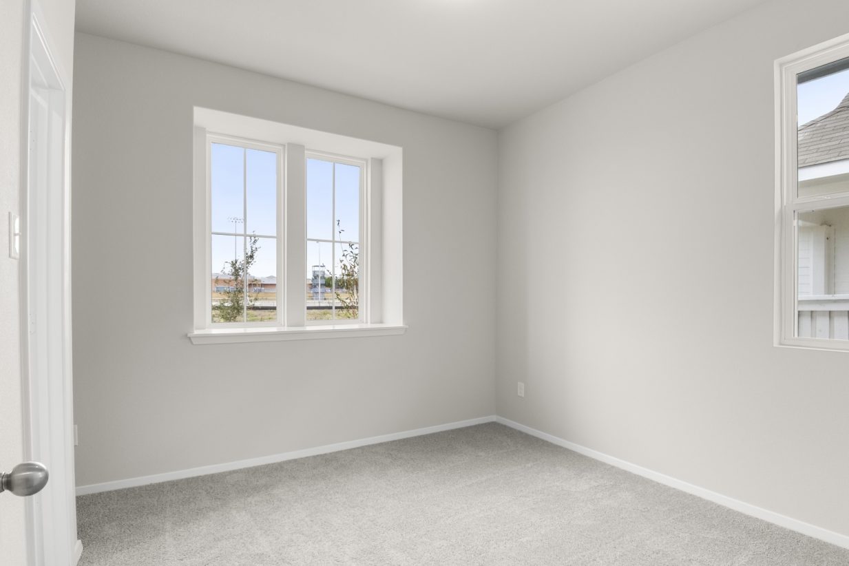 Image of second bedroom with light carpet and floors with a window