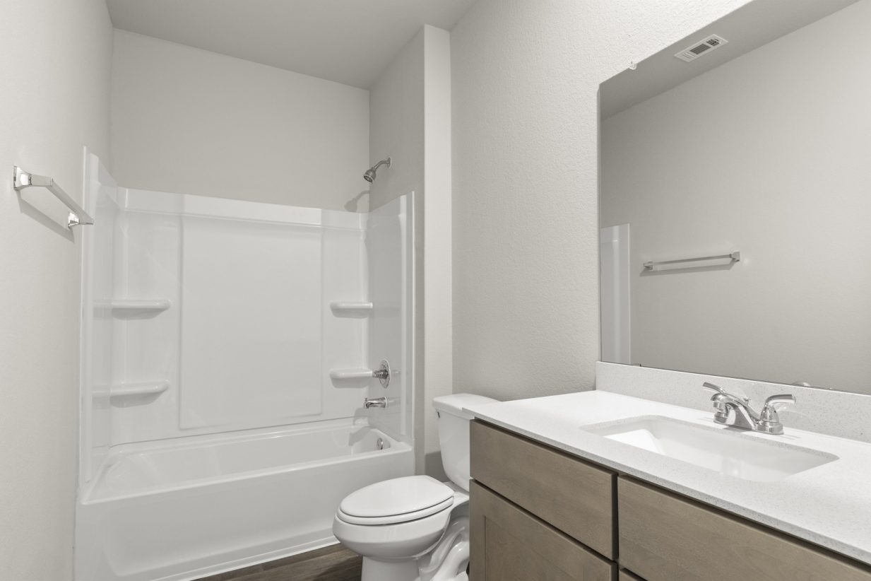 Image of a bathroom with a white vanity and mirror, and a white shower and tub