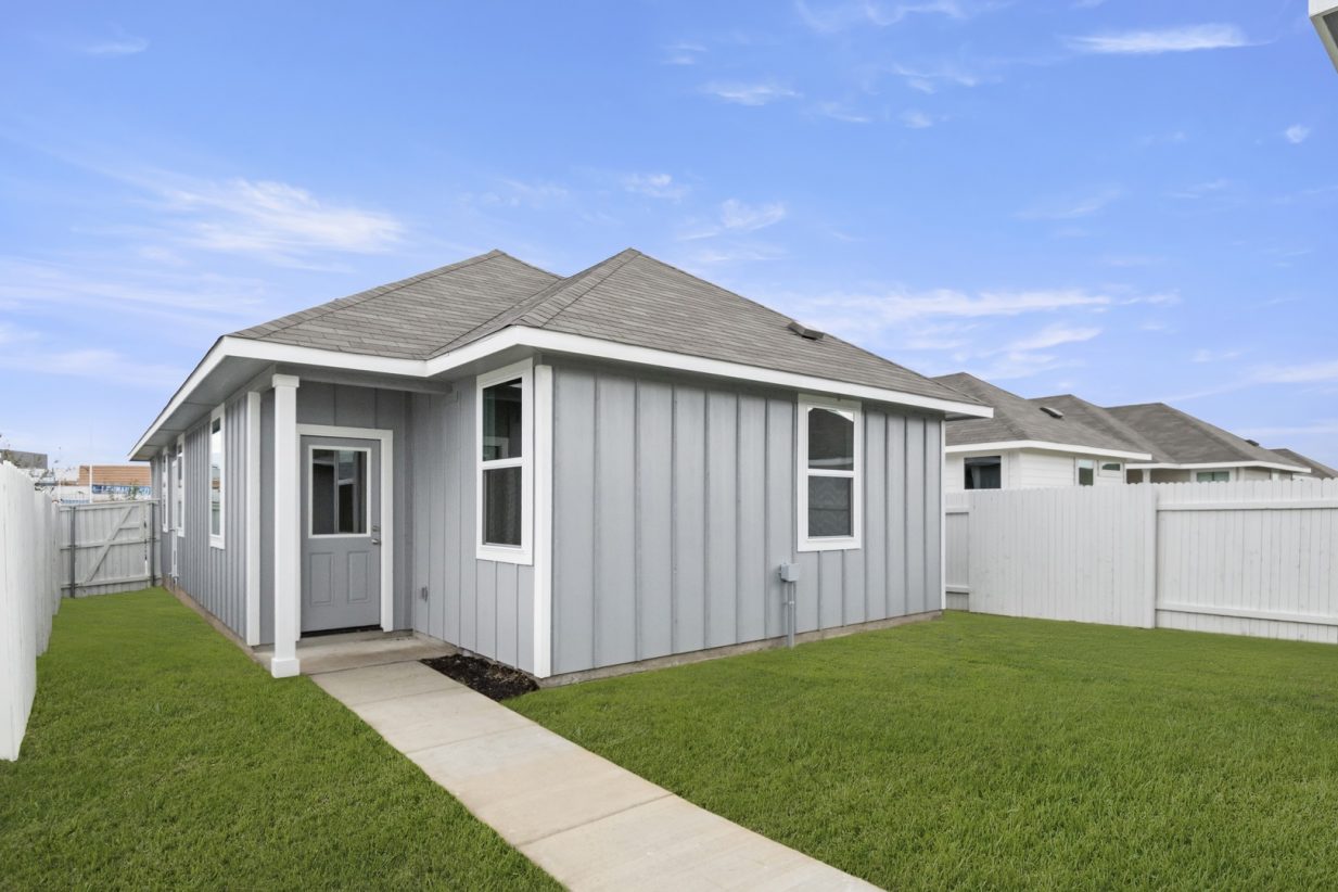 Image of backyard and exterior of grey home with a back door and walk way