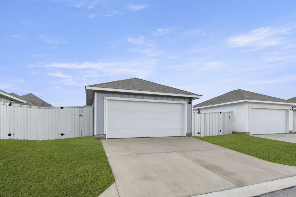 Image of exterior of a two car garage with a cement drive way and a blue sky