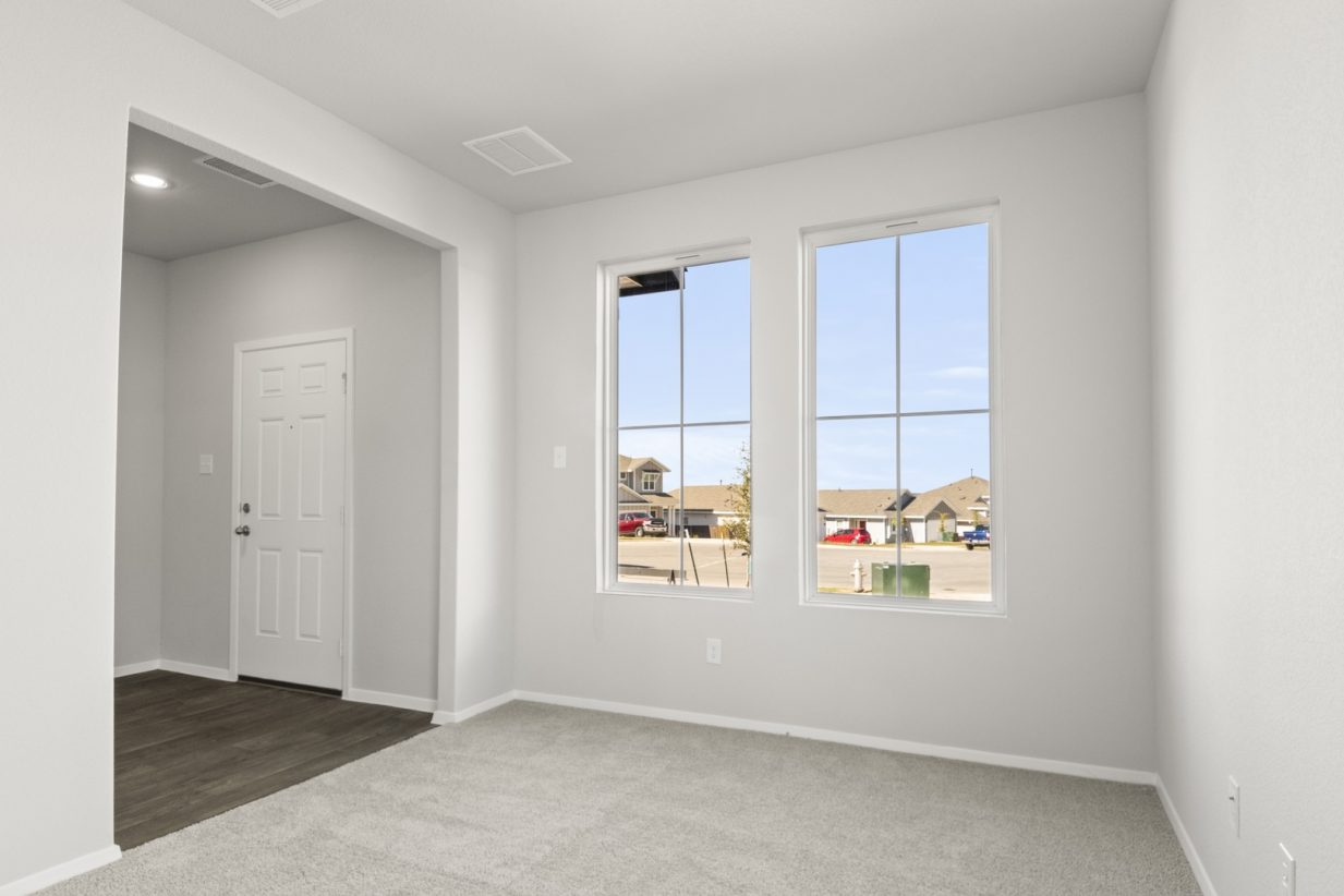 Image of an office space with tan carpeting and light grey painted walls with two windows