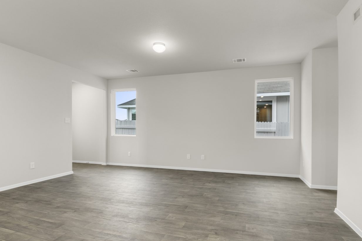 Image of a one story home living room with brown flooring and two windows