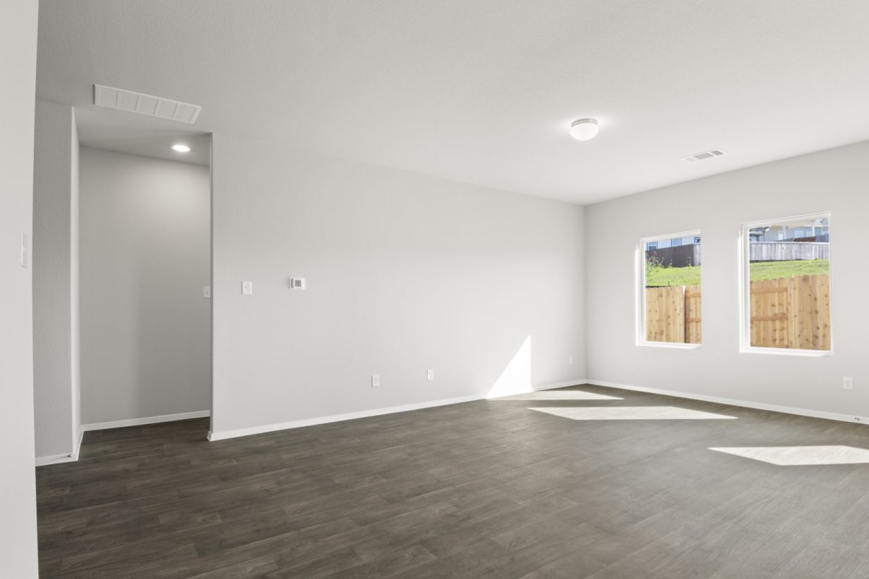 Image of a living room area with dark brown wood-like flooring and light grey painted walls