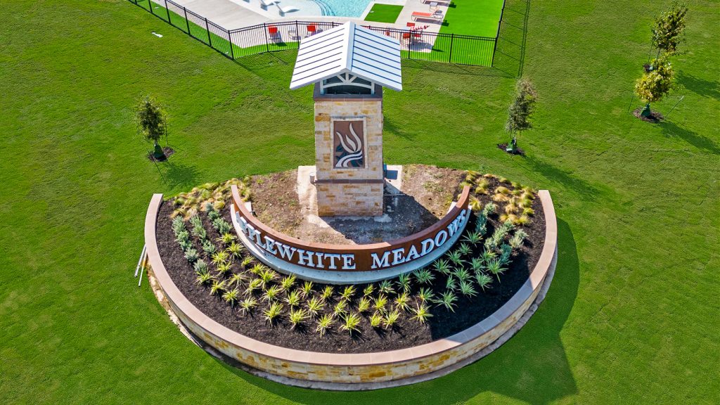 Aerial photo of community monument sigh for Applewhite Meadows surrounded by landcaping and grass with pool in the background