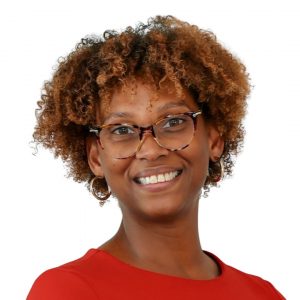 Headshot of woman with auburn curly hair, glasses, red blouse, and earrings