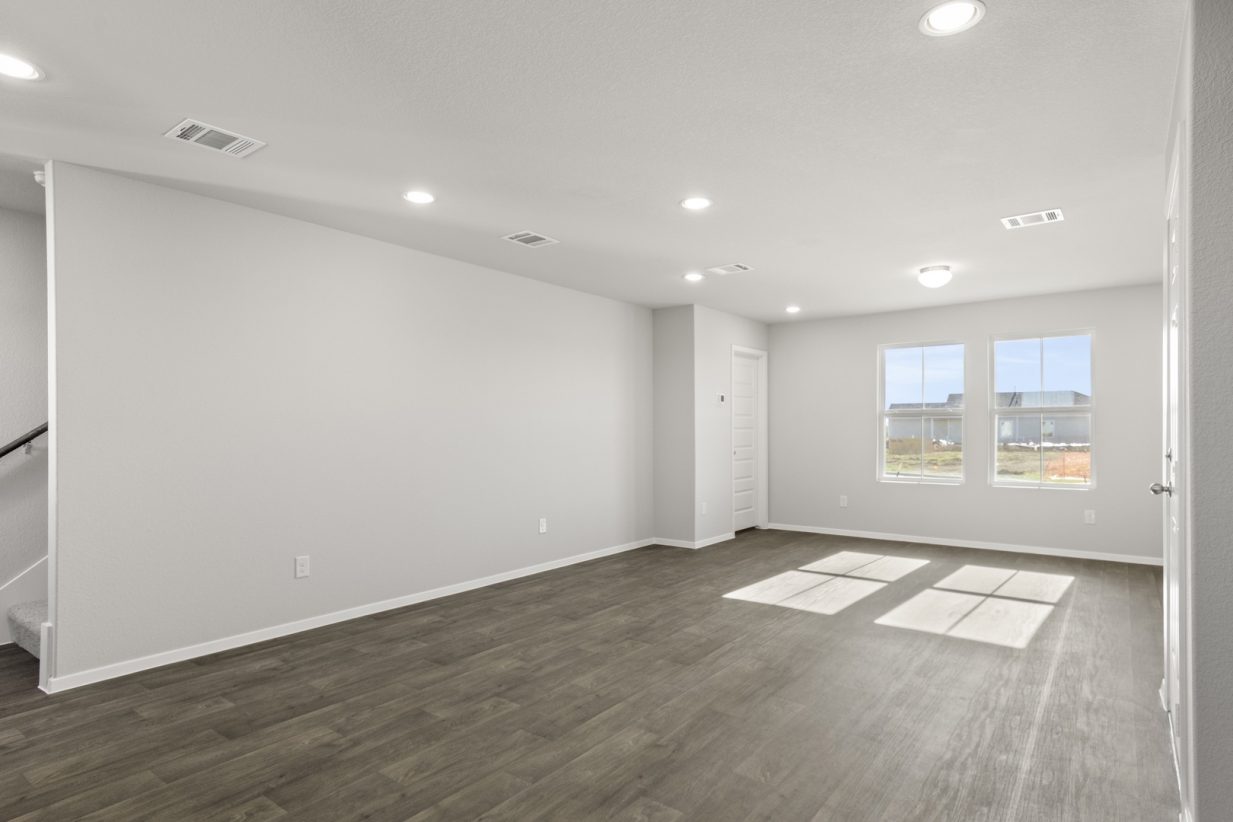 Image of a cottage home living/dining room with dark vinyl flooring, light grey walls and two large windows
