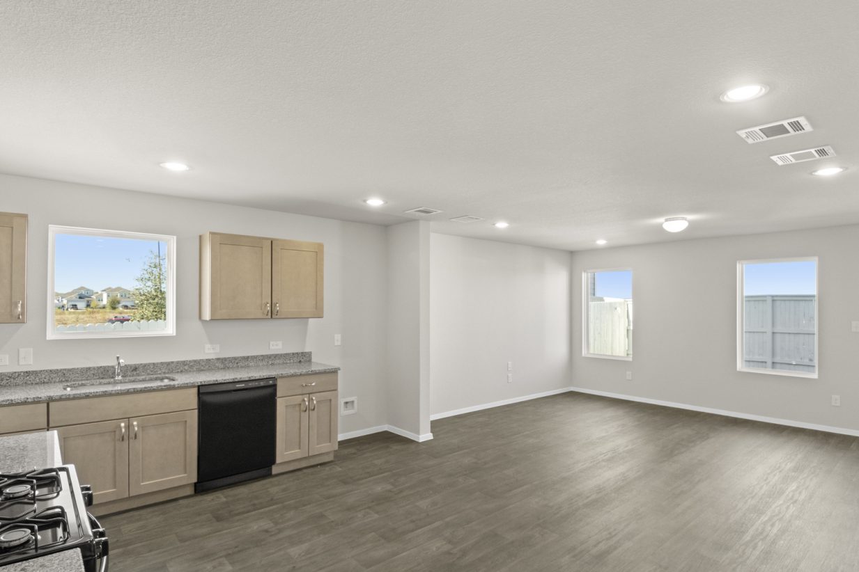 Image of a kitchen/living overview with a window over the sink and windows viewing the backyard