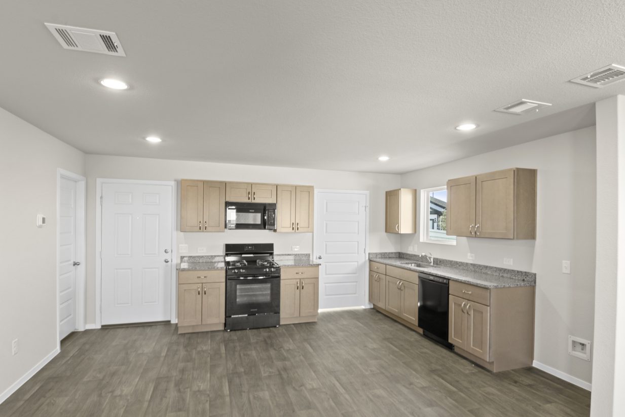 Image if a kitchen with light brown cabinets, granite countertops, and black appliances