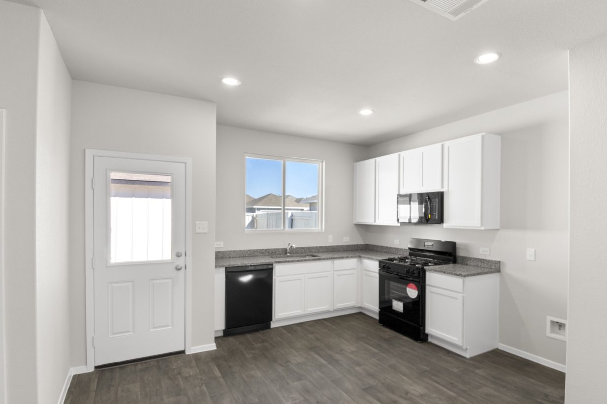 Image of a kitchen with white cabinets, granite countertops, black appliances and a white back door