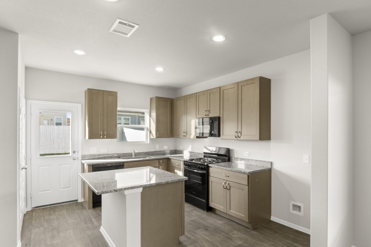 Image of a kitchen with a center island with granite counter tops, brown cabinets and black appliances