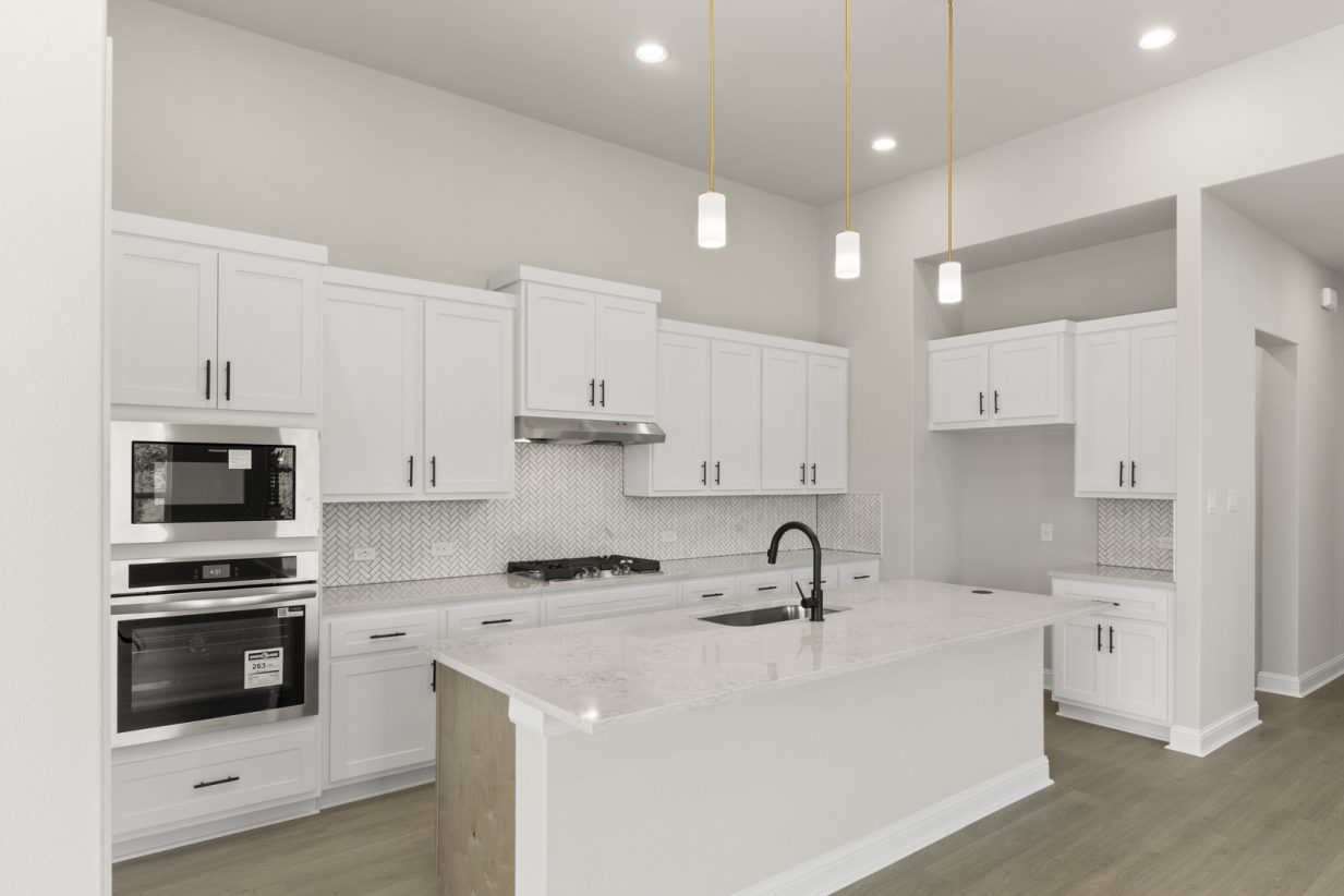 Image of a two story home kitchen with white cabinets, a center island, stainless steel appliances and white backsplash