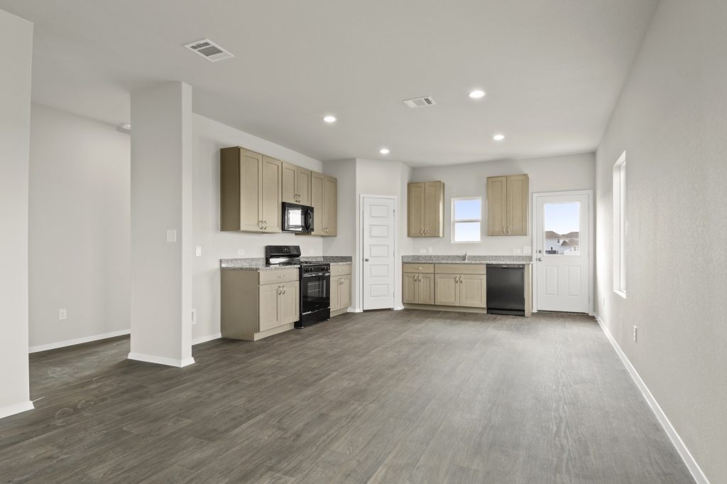 Image of kitchen with brown flooring and light grey walls with light brown cabinets and black stove