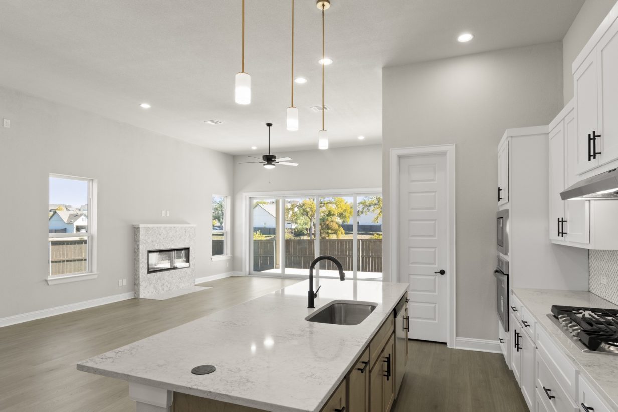 Image of a two story home kitchen with white cabinets, a center island, stainless steel appliances and white backsplash