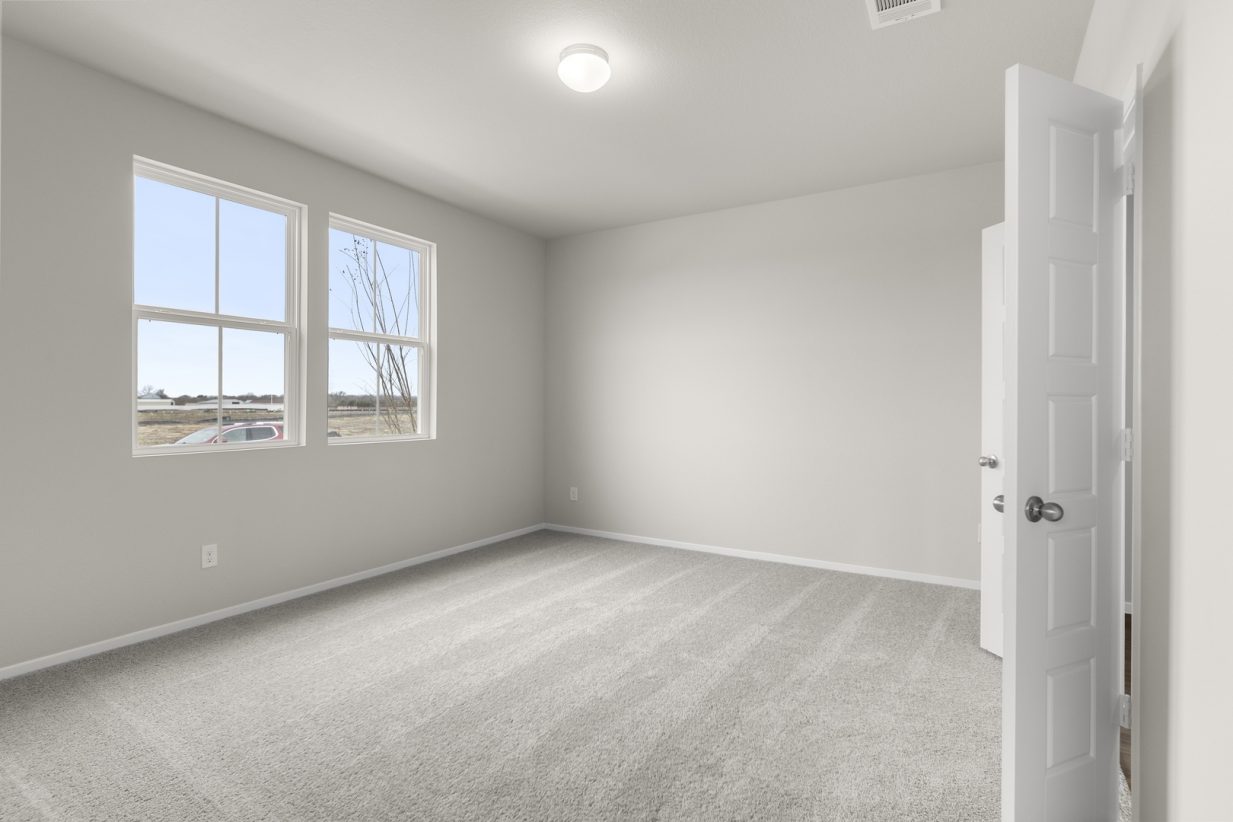 Image of a bedroom with cream walls, tan carpeting, windows, and white trim