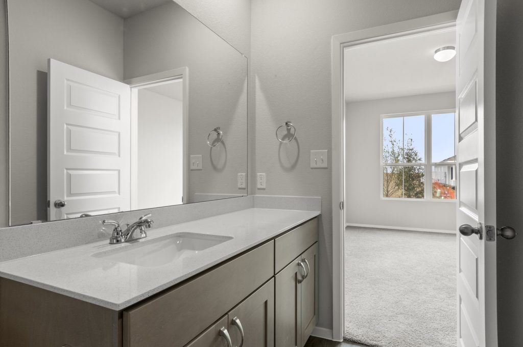 Image of primary bathroom with mirror and white top vanity connected to primary bedroom