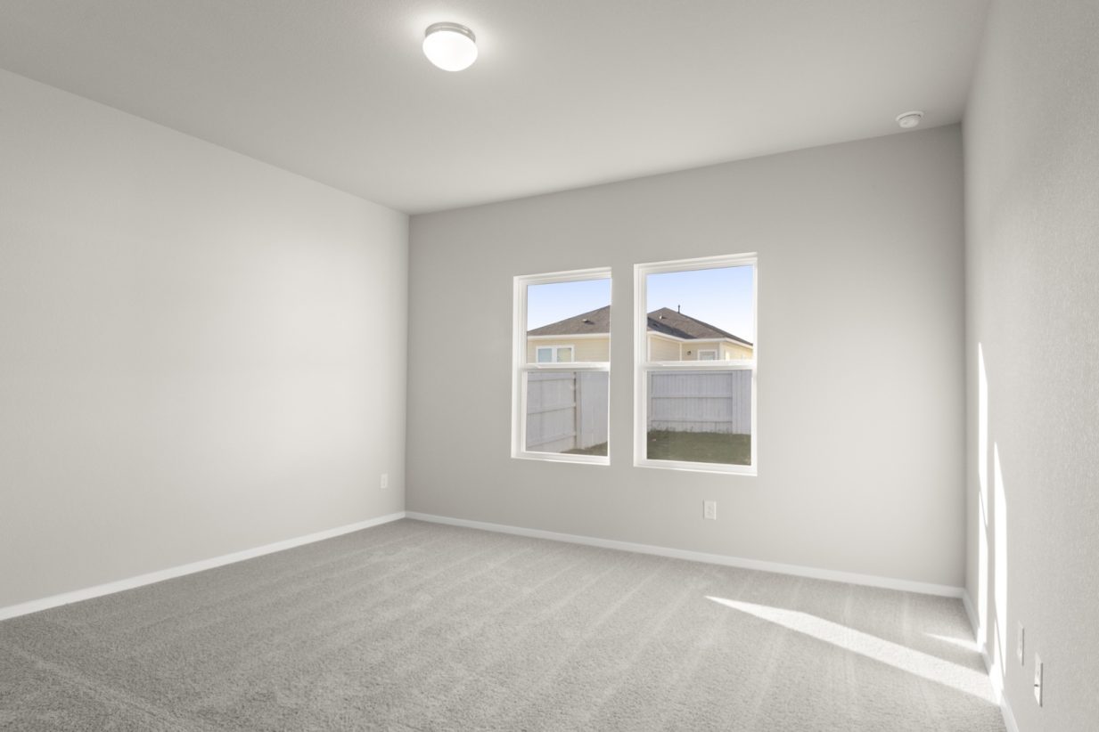 Image of primary bedroom with tan carpeting and light grey painted walls with two windows