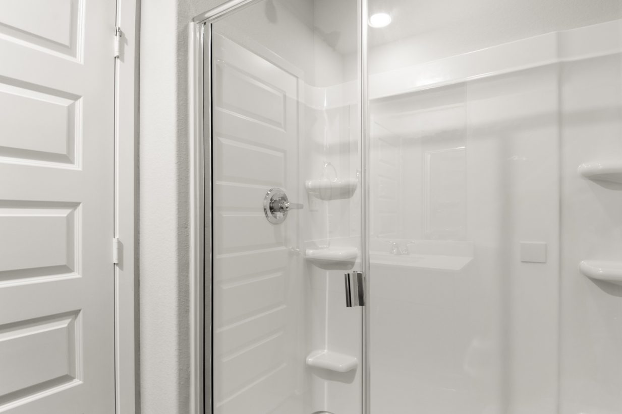 Image of a primary bathroom with a white vinyl walk-in shower