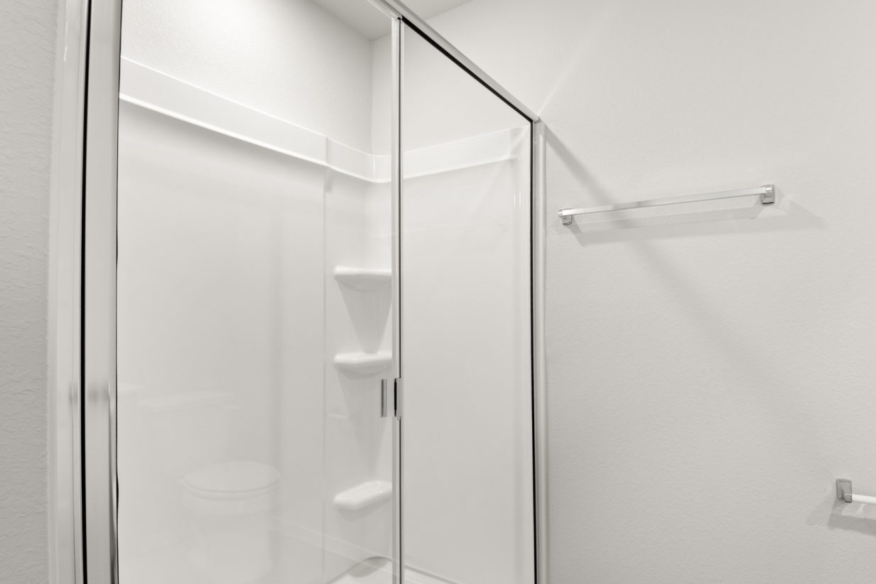 Image of a walk-in shower with white vinyl and a clear pane